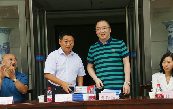 新乡市牧野区税务局党委书记、局长樊保峰向拼搏手机版（中国）党委书记张会民赠送税法知识书籍.jpg